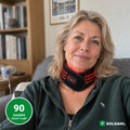 Kvinne i sofaen med Soldahl nakkebånd med rødt lys rundt nakken
