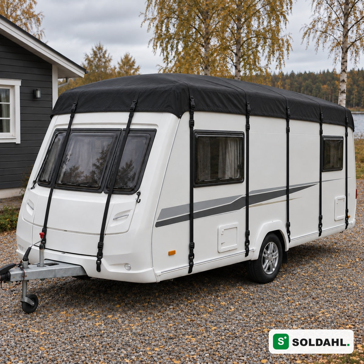 Svart taktrekk montert på hvit campingvogn i en grusinnkjørsel